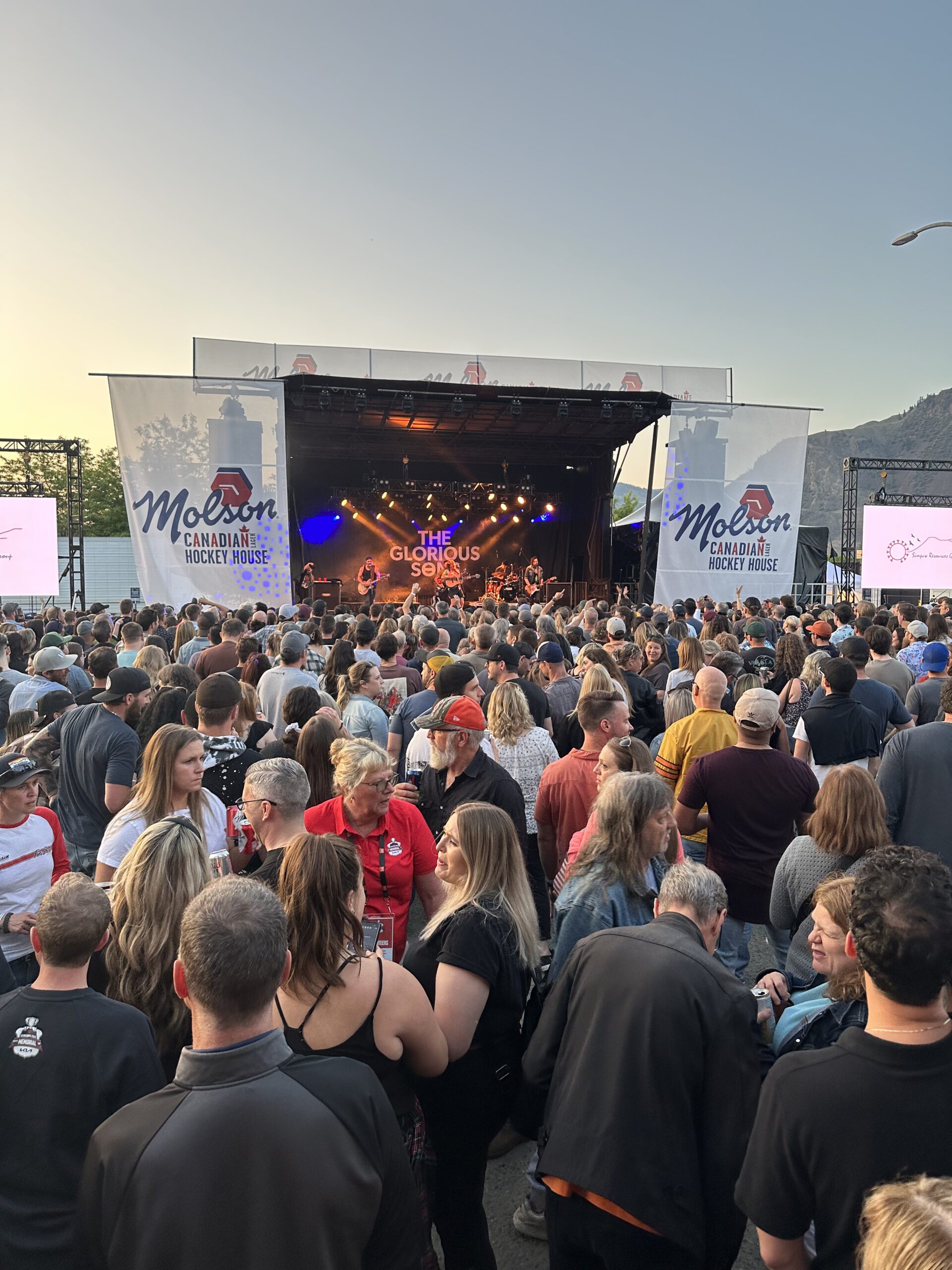 an outdoor stage line with the glorious sons playing infront of a crowd